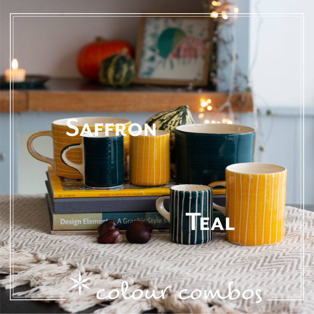 A selection of teal and saffron mugs in a range of different shapes against a background of grey blankets, books, conkers and pumpkin.