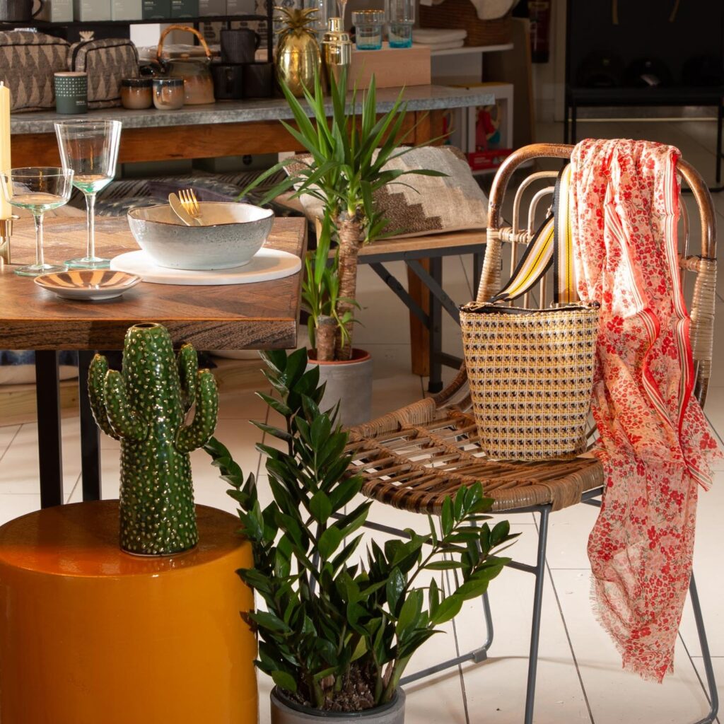 Image featuring an array of plants alongside a dining table setup and Serax Ochre side table. One chair is pulled out with a bag and a scarf on it.