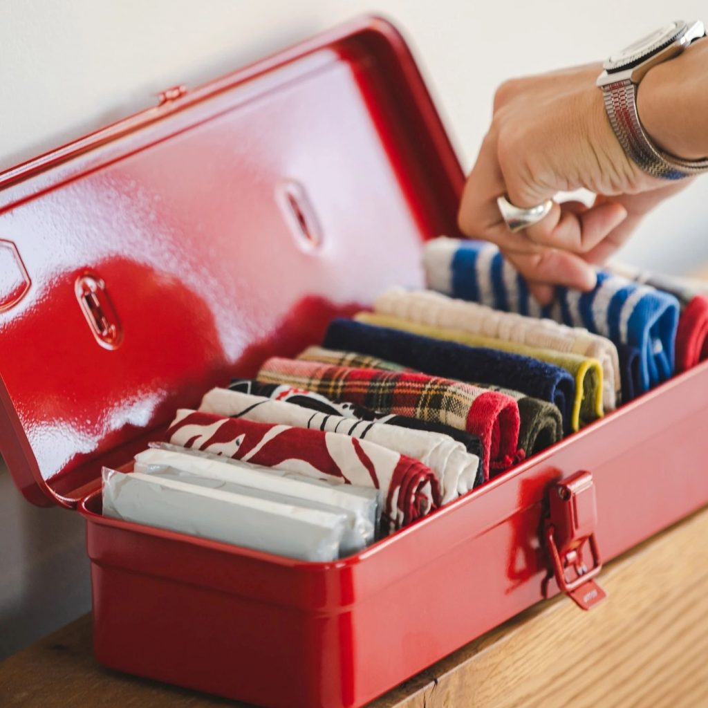 Image features a red steel box full of folded colourful clothes